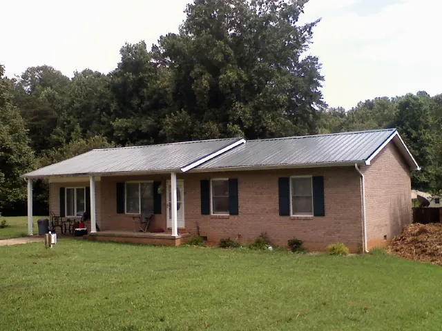 Gray metal roof on a brick ranch house with a side carport in Murdock