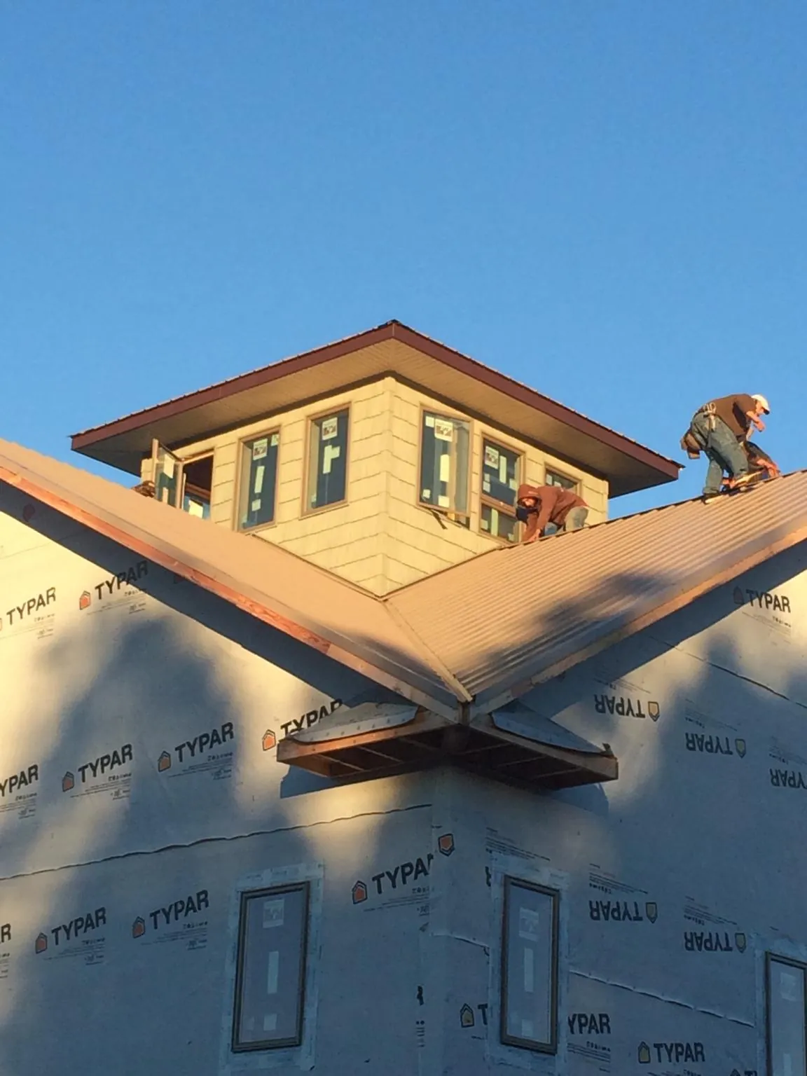 Roofers working around a rooftop cupola on a new metal roof at sunset — Roof Waterproofing in Murdock by Roofing Brothers